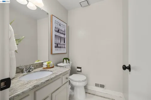 a bathroom with a granite countertop toilet sink and mirror