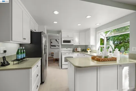 a kitchen with a refrigerator a stove a sink dishwasher a oven with white cabinets and wooden floor