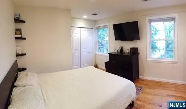 a bedroom with a bed and a flat tv screen on dresser