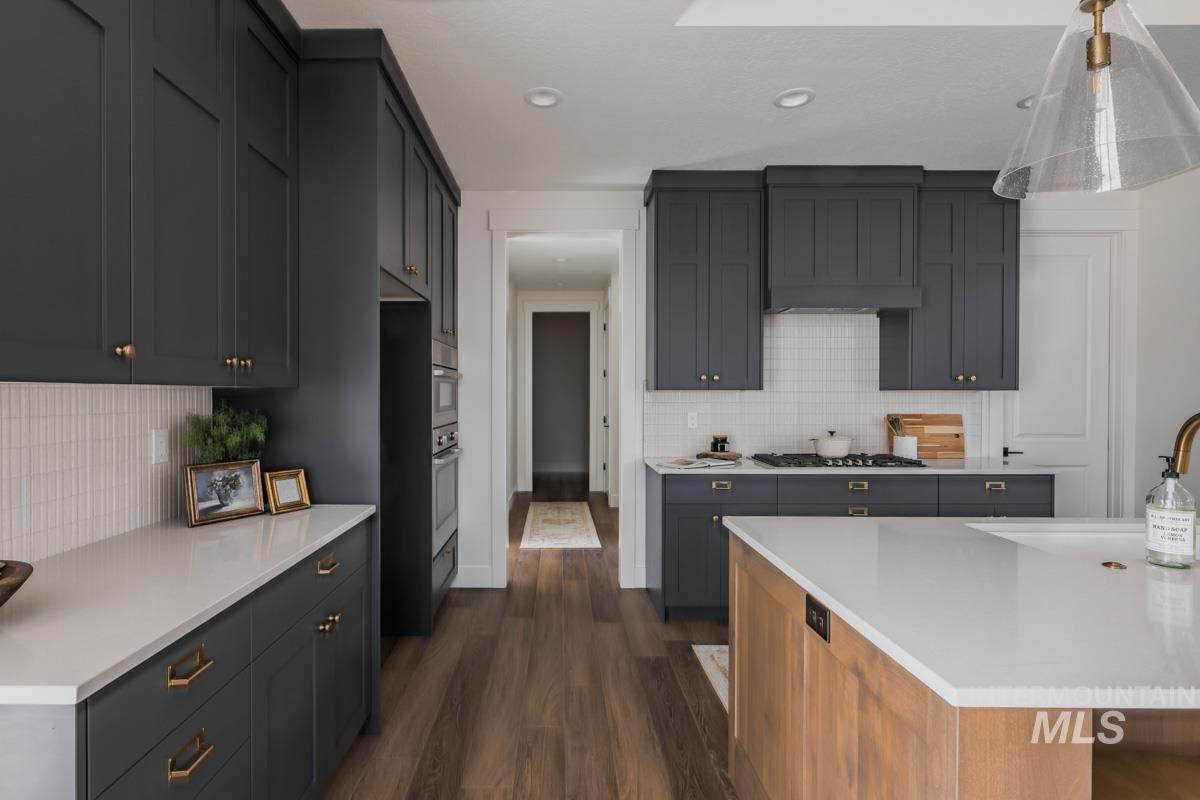 6091 South Apex Avenue Meridian, ID 83642 - Photo 18 of 40 Kitchen with dark wood finished floors, backsplash, hanging light fixtures, light stone countertops, and recessed lighting