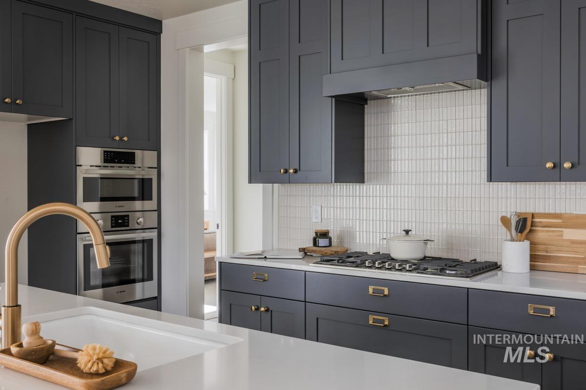 6091 South Apex Avenue Meridian, ID 83642 - Photo 22 of 40 Kitchen featuring decorative backsplash, stainless steel appliances, light stone countertops, and gray cabinetry