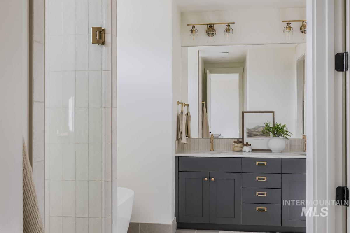 6091 South Apex Avenue Meridian, ID 83642 - Photo 26 of 40 Full bath with double vanity, a soaking tub, and tasteful backsplash