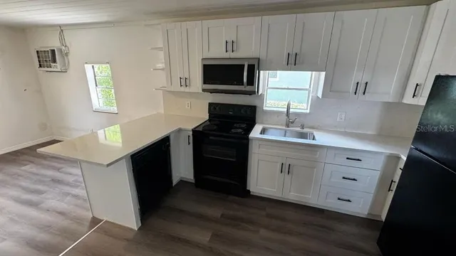 a kitchen with white cabinets a stove top oven a sink and dishwasher