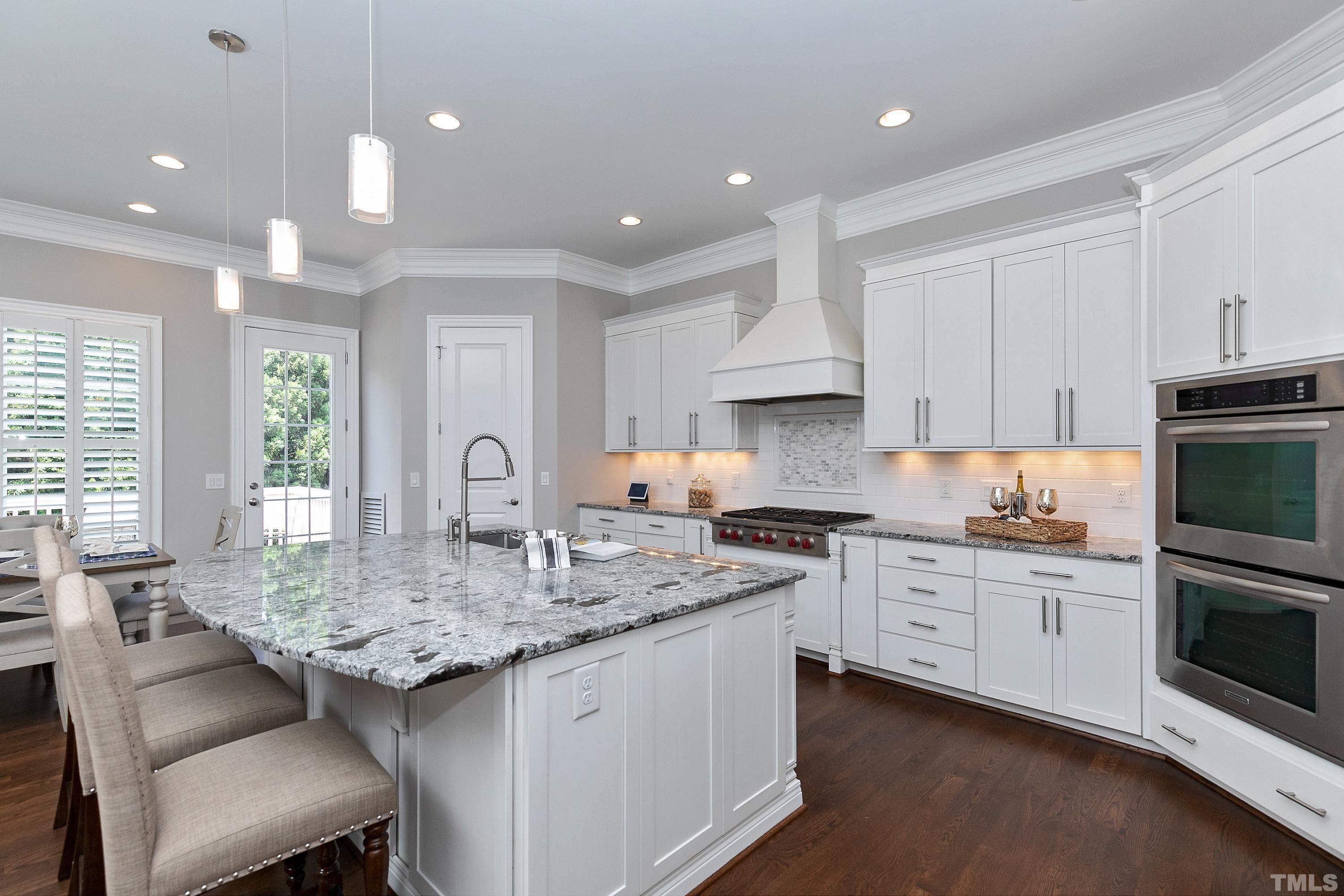 302 Michelangelo Way Cary, NC 27518 - Photo 5 of 44 a kitchen with granite countertop a stove a sink a refrigerator and white cabinets with wooden floor