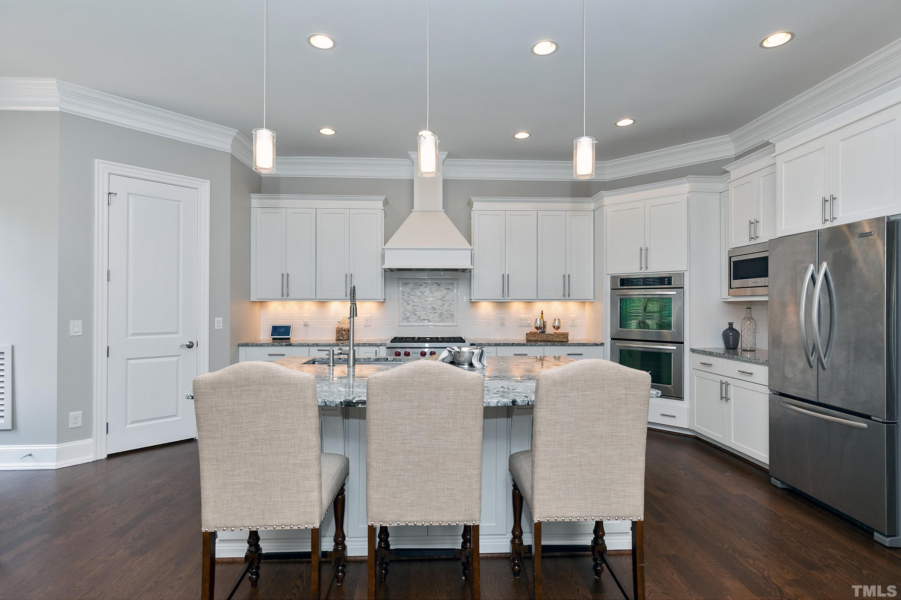 302 Michelangelo Way Cary, NC 27518 - Photo 9 of 44 a kitchen with stainless steel appliances granite countertop a dining table chairs refrigerator and cabinets