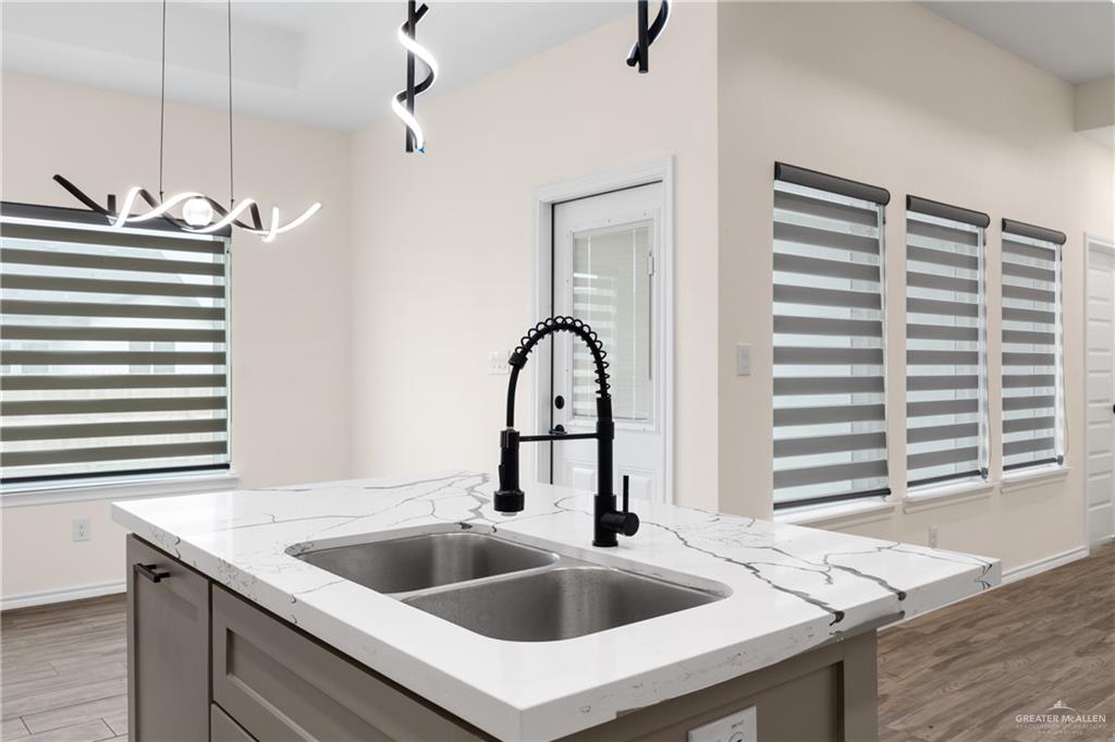 18054 Spruce Street Combes, TX 78552 - Photo 9 of 25 Kitchen island with a double stainless steel sink, black gooseneck faucet, and veined white countertop