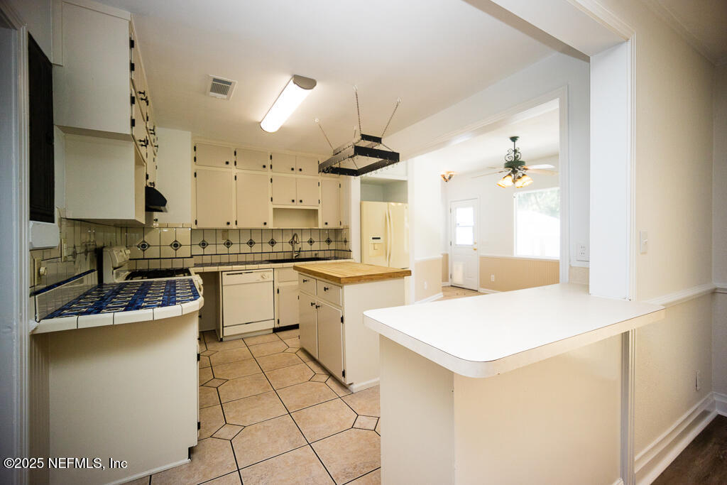 9965 Arnold Road Jacksonville, FL 32246 - Photo 22 of 60 a kitchen with a sink a stove a refrigerator and white cabinets