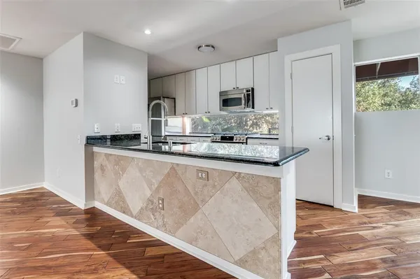 a kitchen with stainless steel appliances granite countertop a stove a sink and a microwave