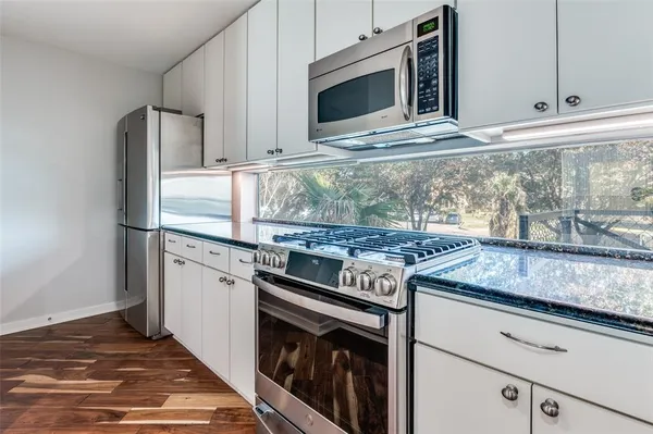 a kitchen with granite countertop cabinets stainless steel appliances and wooden floor