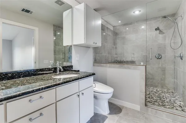 a bathroom with a granite countertop sink a toilet and shower