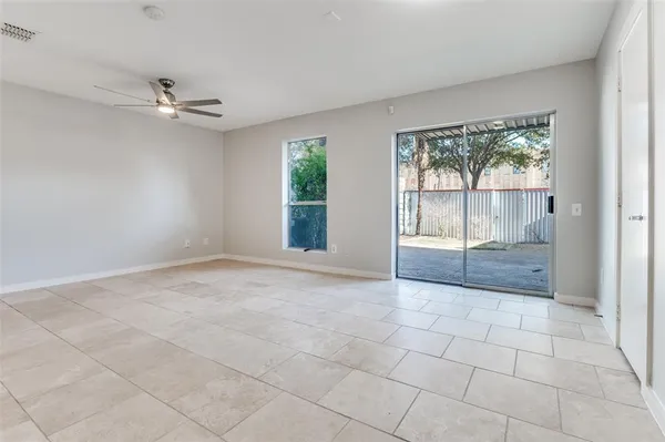 an empty room with chandelier fan and windows