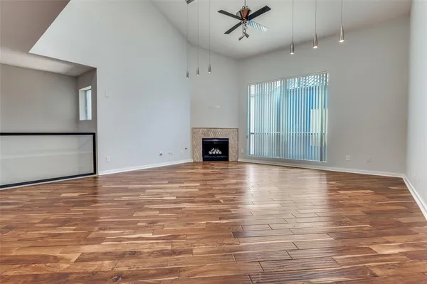 an empty room with wooden floor fireplace and windows