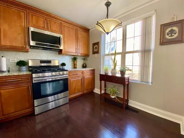 a kitchen with stainless steel appliances wooden floors and a view of living room