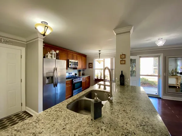 a kitchen with stainless steel appliances kitchen island granite countertop a refrigerator and a sink
