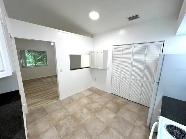 an empty room with wooden floor chandelier fan and windows
