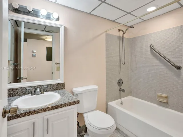 a bathroom with a granite countertop sink a mirror a toilet and bathtub