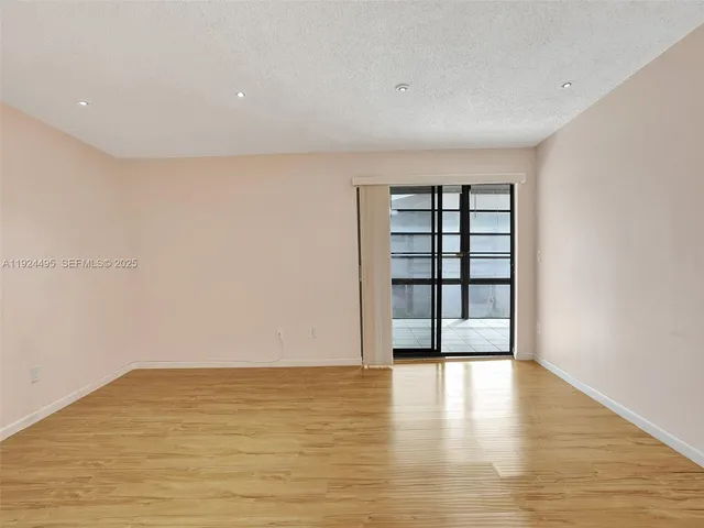 a view of an empty room with wooden floor and window