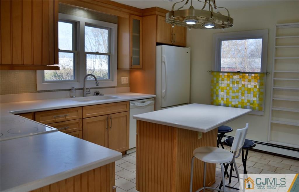 292 Georges Road Dayton, NJ 08810 - Photo 5 of 19 a kitchen with stainless steel appliances kitchen island a table chairs in it and wooden floors