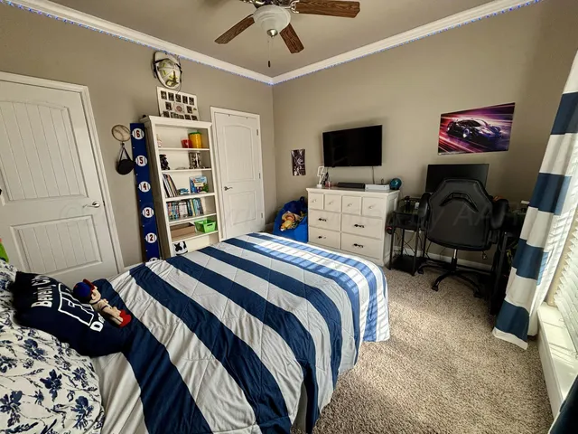 a bedroom with a bed a computer on the desk and a book shelf