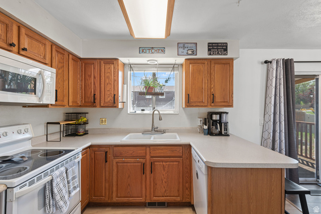 3951 Brixton Road Salt Lake City, UT 84129 - Photo 10 of 22 Kitchen featuring wood cabinetry, white countertops, built-in microwave, white electric range, and a single basin sink under a window
