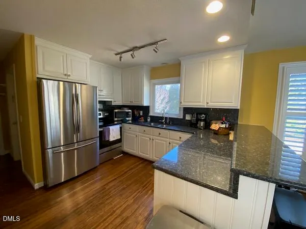 a kitchen with stainless steel appliances granite countertop wooden floors a stove a sink and a microwave