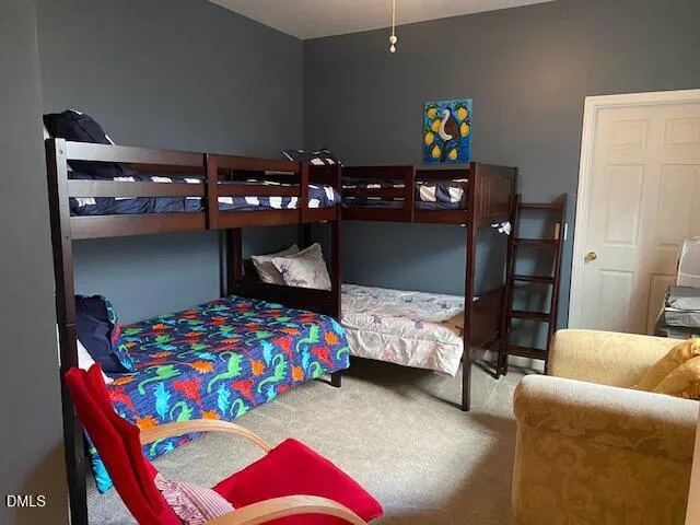 a bedroom with a bed and a lamp on dresser