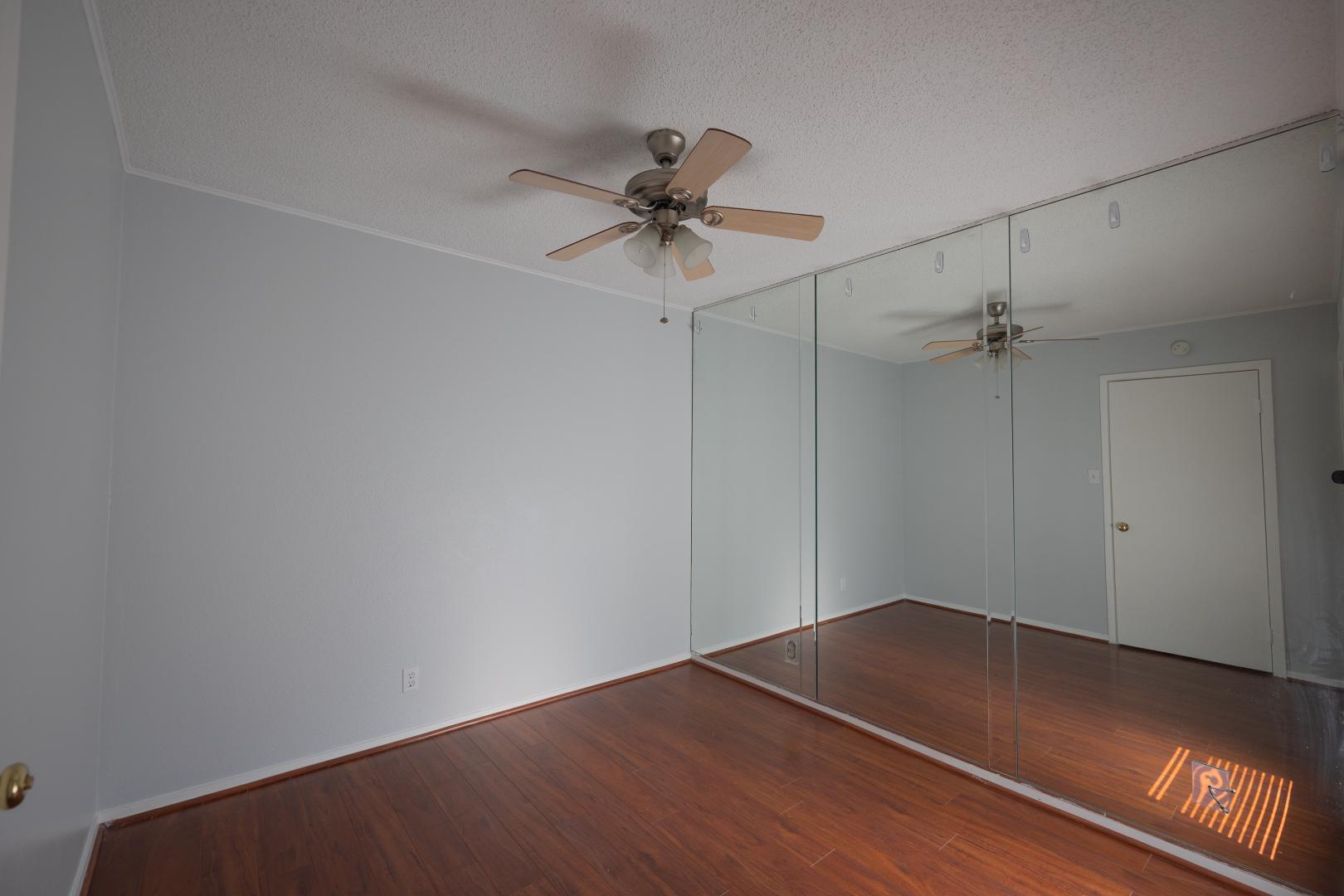 2110 Rio Grande Street, Unit 307 Austin, TX 78705 - Photo 7 of 12 Rich hardwood-style flooring extends across this tranquil space, reflecting natural light from the mirrored closet doors.
