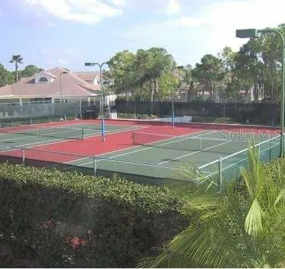 a view of a tennis ground with large trees