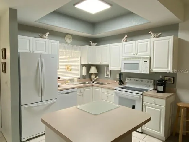 a kitchen with a sink a refrigerator a stove and white cabinets