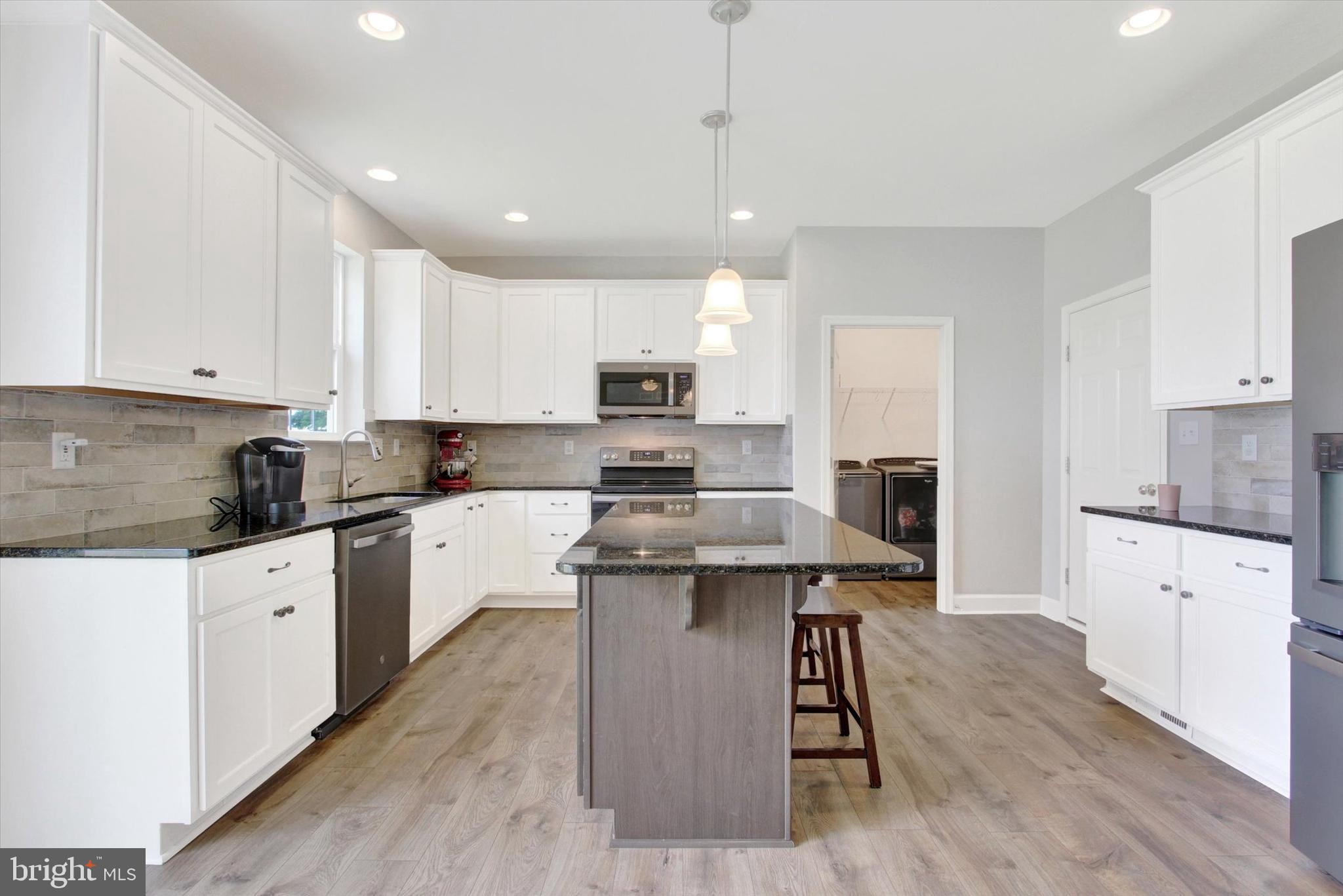 49 Red Rock Run Hanover, PA 17331 - Photo 8 of 38 a kitchen with stainless steel appliances granite countertop a stove top oven a sink dishwasher a refrigerator and white cabinets with wooden floor