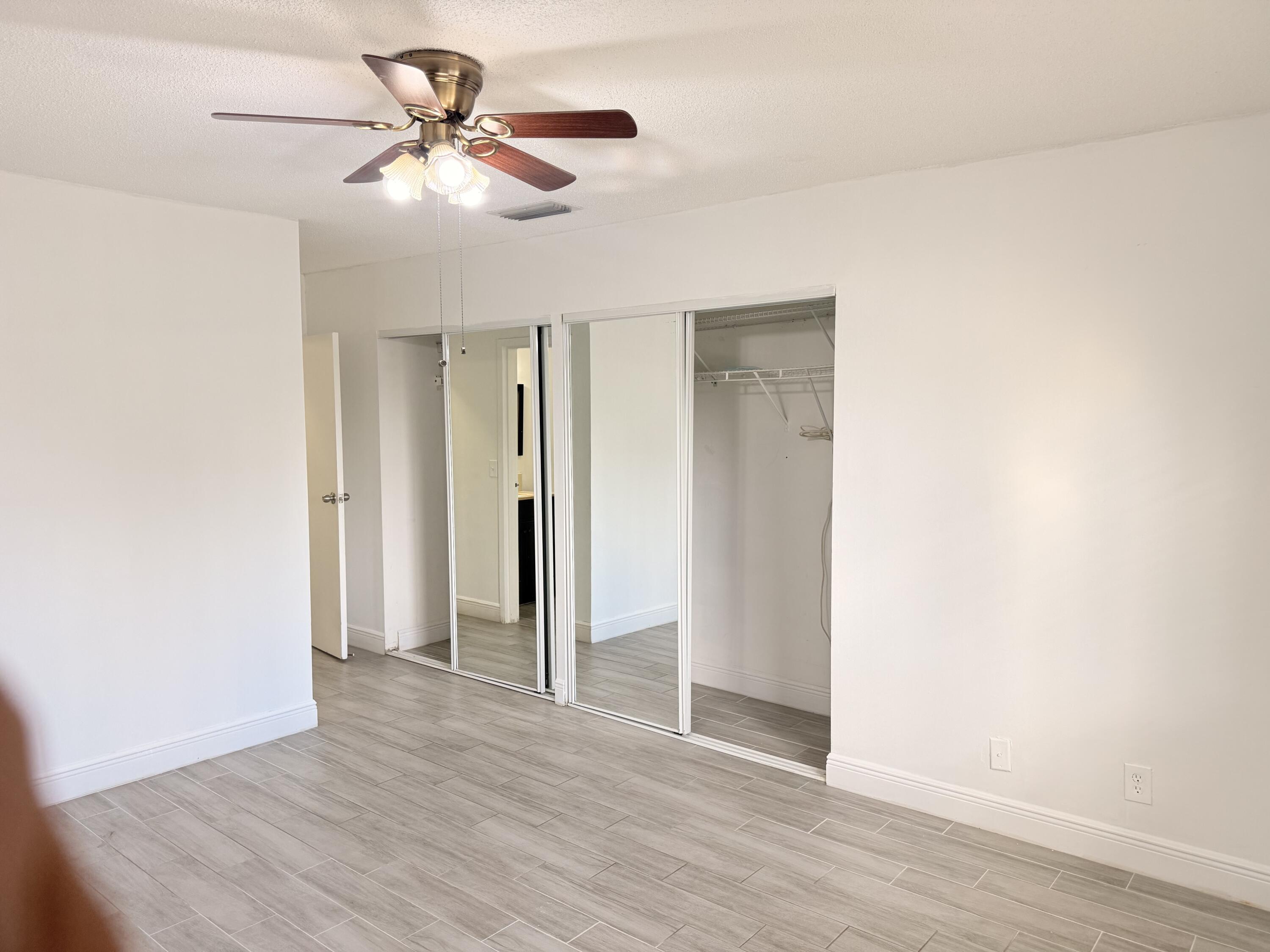 906 Southwest 9th St Circle, Unit 204 Boca Raton, FL 33486 - Photo 11 of 39 an empty room with wooden floor and ceiling fan