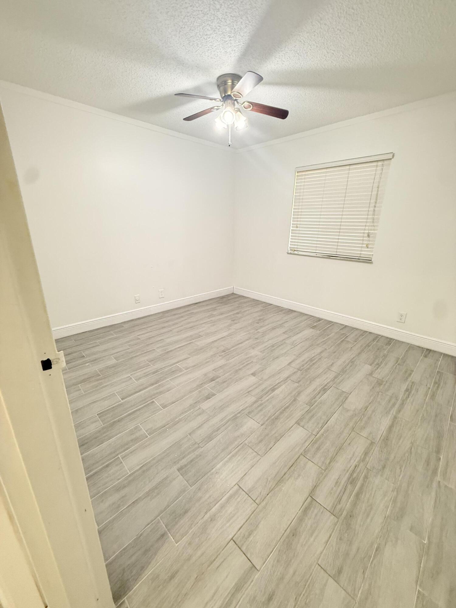906 Southwest 9th St Circle, Unit 204 Boca Raton, FL 33486 - Photo 16 of 39 an empty room with wooden floor fan and windows