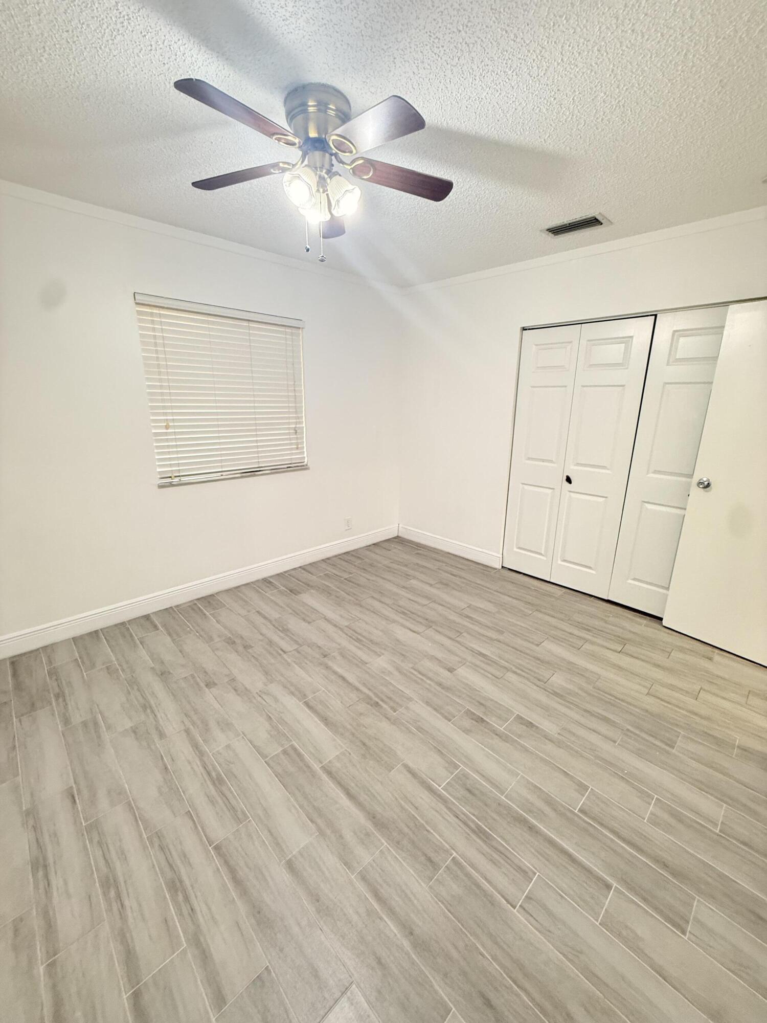 906 Southwest 9th St Circle, Unit 204 Boca Raton, FL 33486 - Photo 17 of 39 an empty room with wooden floor fan and windows