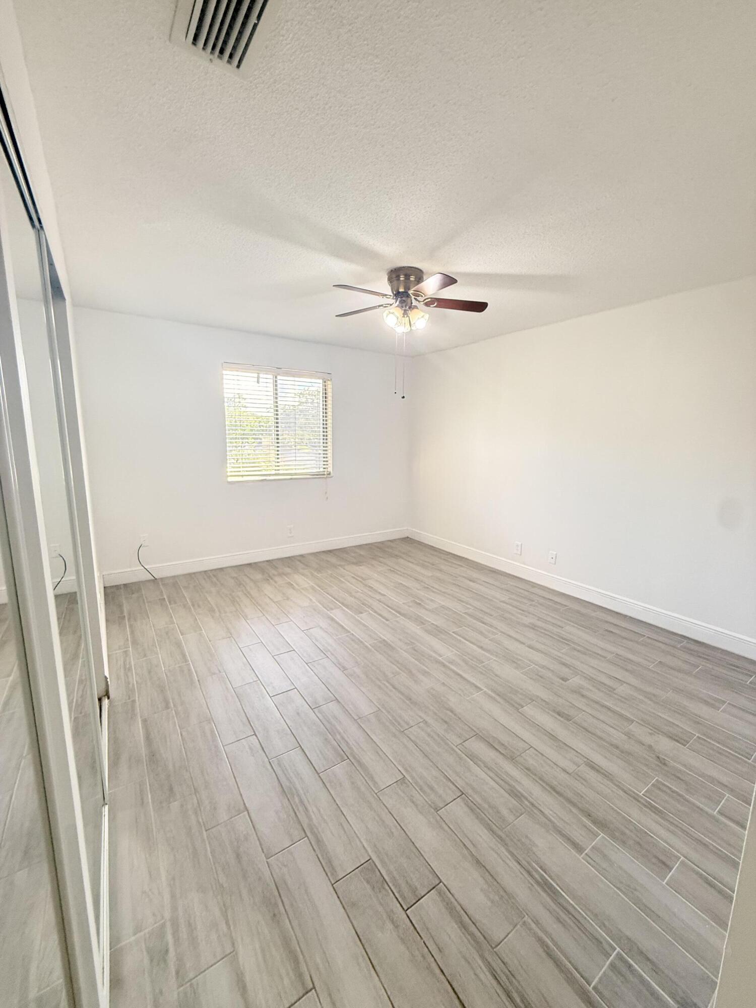 906 Southwest 9th St Circle, Unit 204 Boca Raton, FL 33486 - Photo 9 of 39 an empty room with wooden floor and windows