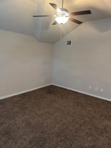 an empty room with a fan & a ceiling fan