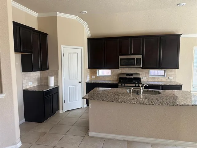 a kitchen with stainless steel appliances granite countertop a refrigerator a stove top oven a sink and dishwasher