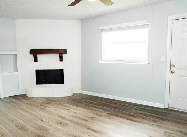 a view of empty room with wooden floor and fireplace