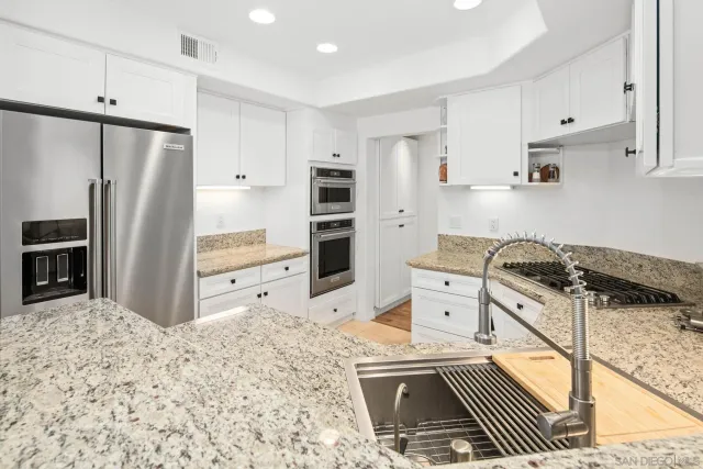 a kitchen with granite countertop a stove sink and cabinets