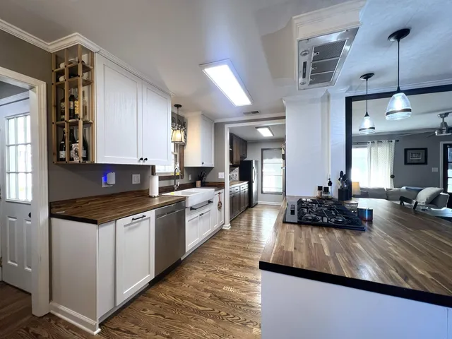 a kitchen with kitchen island granite countertop a sink cabinets and wooden floor