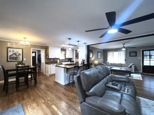 a living room with furniture kitchen view and a wooden floor
