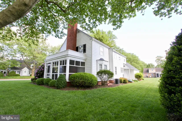 a view of a yard in front of a house with plants and large trees