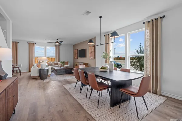 a view of a dining room and livingroom with furniture wooden floor a rug a painting and a chandelier
