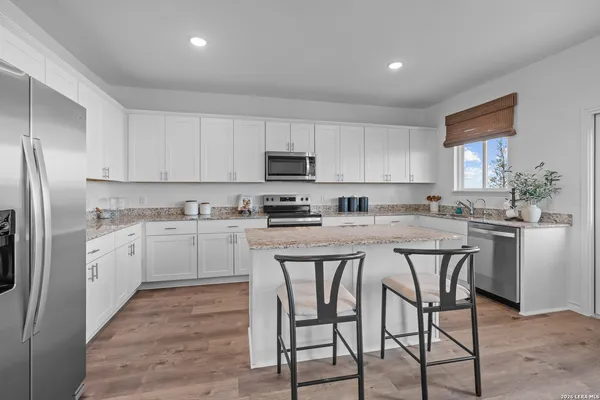 a kitchen with stainless steel appliances granite countertop a white cabinets and a refrigerator