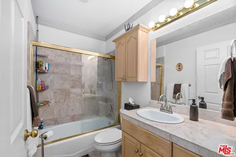 a bathroom with a granite countertop bathtub shower sink vanity mirror and toilet
