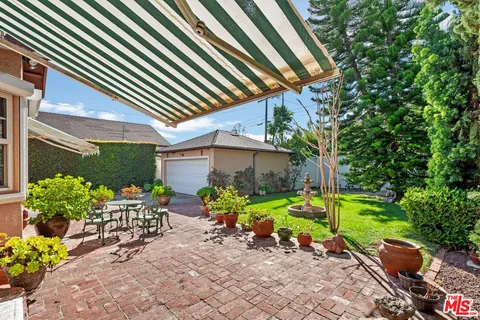 a view of backyard with table and chairs and potted plants