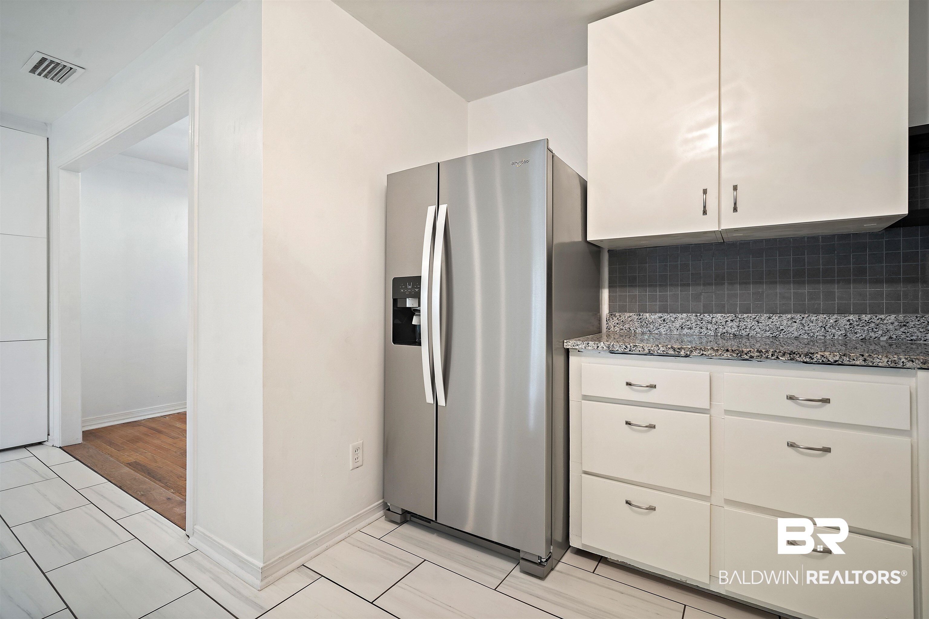 2615 Walton Avenue Mobile, AL 36606 - Photo 15 of 33 Kitchen featuring stainless steel refrigerator with ice dispenser, visible vents, decorative backsplash, white cabinetry, and light stone countertops