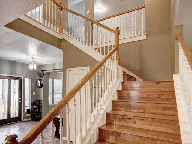 a view of staircase with railing and a chandelier