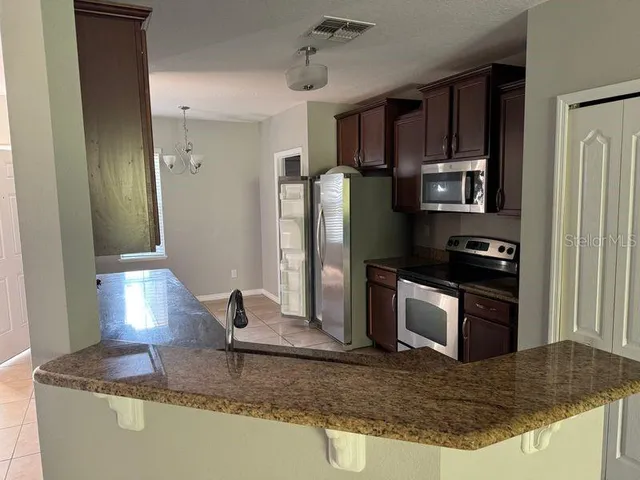 a kitchen with stainless steel appliances granite countertop a refrigerator a stove and a sink with granite countertops