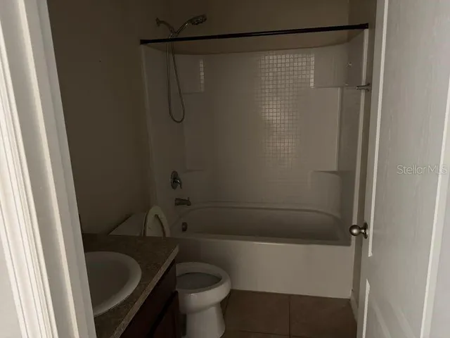 a bathroom with a granite countertop bathtub shower and toilet