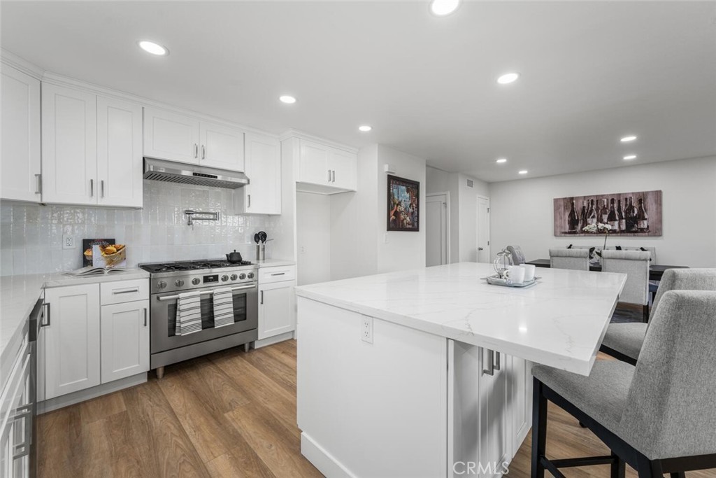 11344 Rochelle Street Los Alamitos, CA 90720 - Photo 13 of 55 a kitchen with stainless steel appliances kitchen island granite countertop a stove a sink a refrigerator and white cabinets with wooden floor
